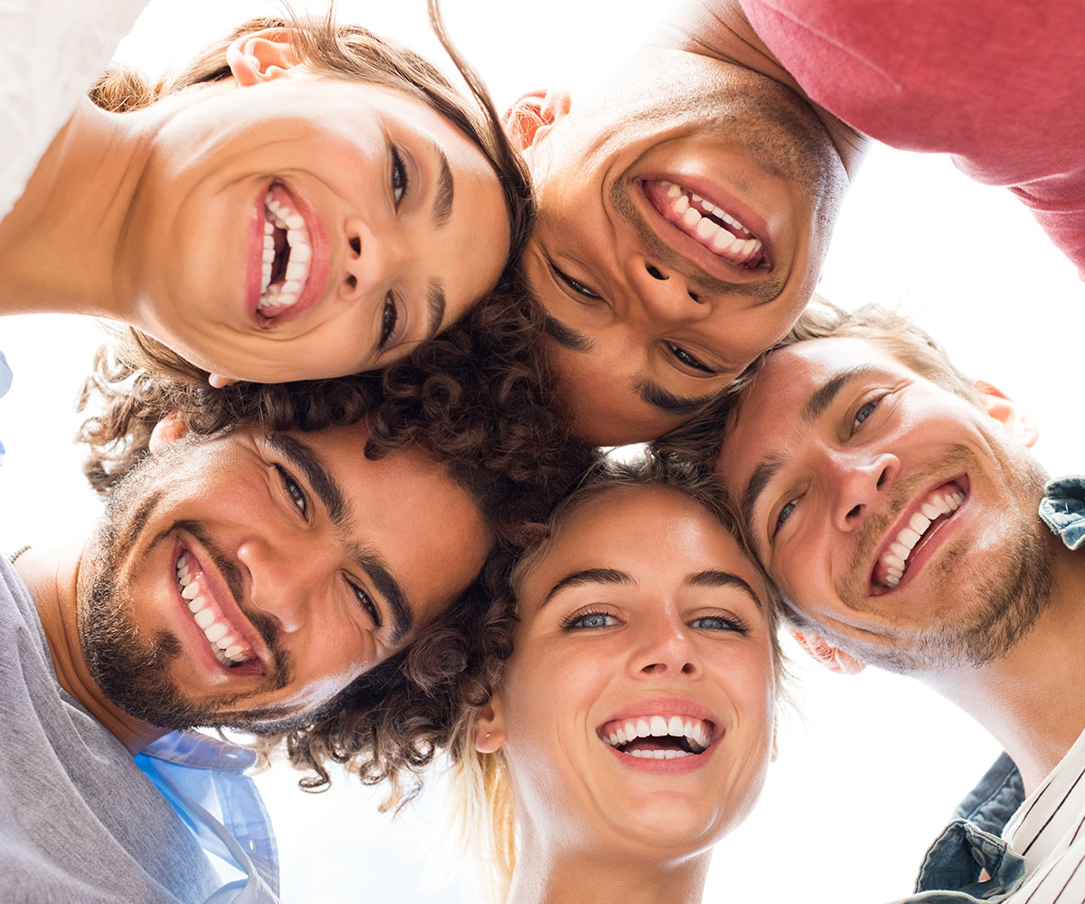 A group of five young adults, three males and two females, smiling and looking directly at the camera.